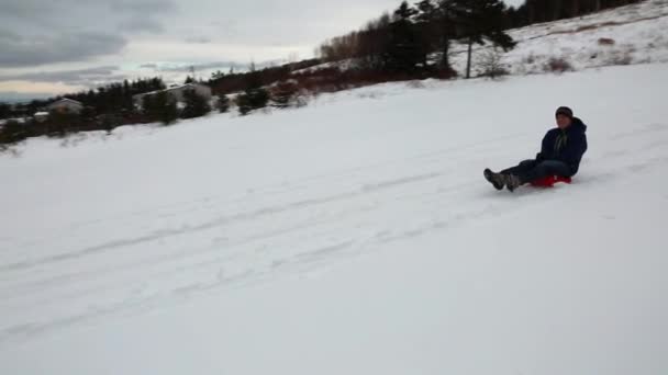 Garçon traîneaux en bas d'une colline — Video