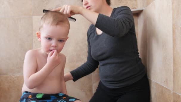 La mujer corta el pelo de un niño — Vídeo de stock