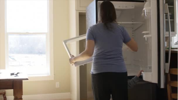 Kleinkind und Mutter räumen Kühlschrank aus — Stockvideo
