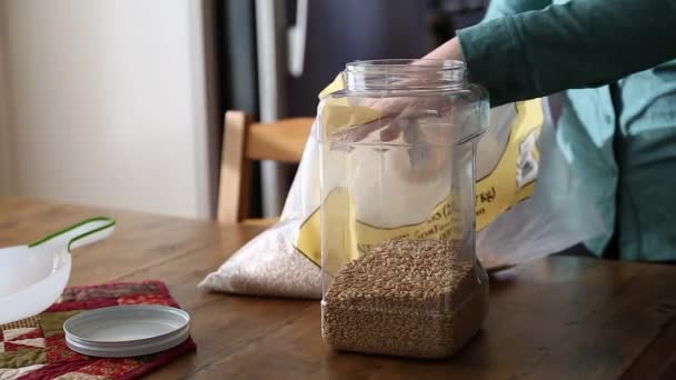 Mujer pone trigo en contenedor de alimentos — Vídeo de stock