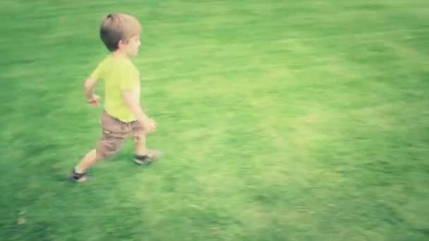 Chico corriendo sobre hierba — Vídeo de stock