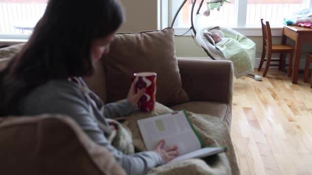 Женщина читает книгу на диване — стоковое видео