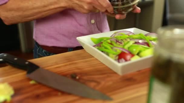 Жінка кладе оливки на салат — стокове відео