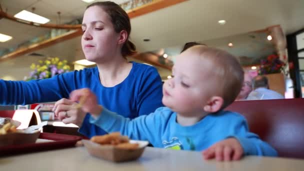 Маленький мальчик ест куриные полоски с мамой — стоковое видео