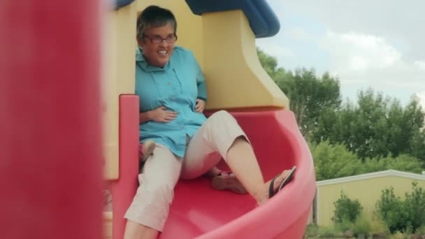 Grandmother and kids going down slide — Stock Video