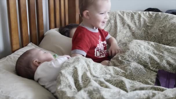 Madre con un bebé y un niño pequeño en su cama — Vídeo de stock