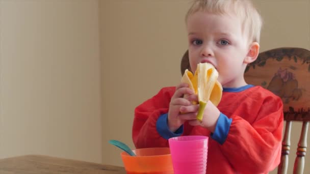 Maluch jedzenie jego banana i zbóż — Wideo stockowe