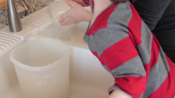 Oddler helps mother clean the dishes — Stock Video