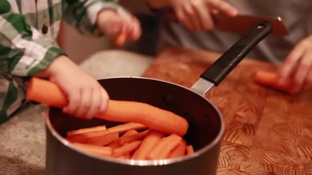 Bambino aiuta mamma tagliare carote — Video Stock