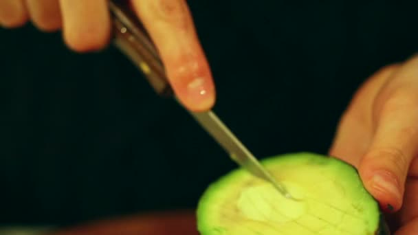 Женщина режет авокадо — стоковое видео