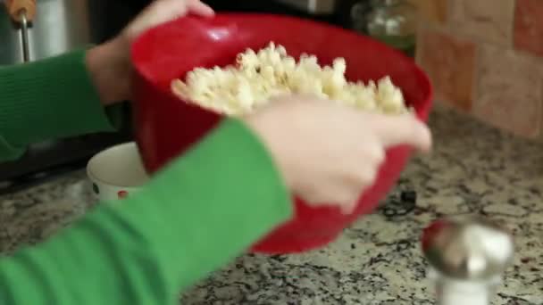 Žena přidává sůl a máslo na popcorn — Stock video