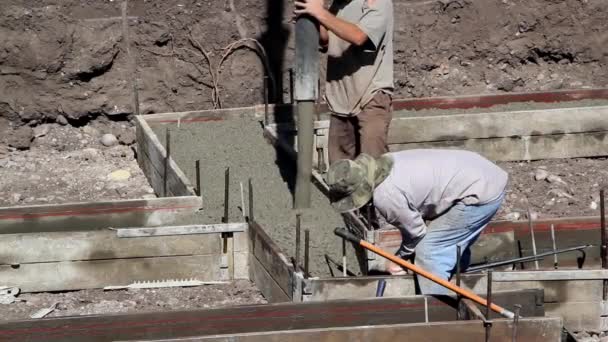 Два рабочих-строителя заливают опоры — стоковое видео