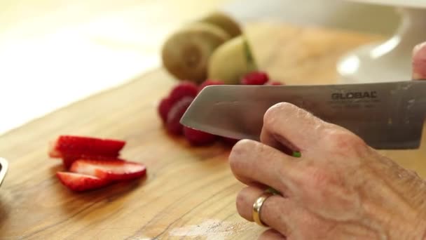 Vrouw snijdt bessen en kiwi — Stockvideo