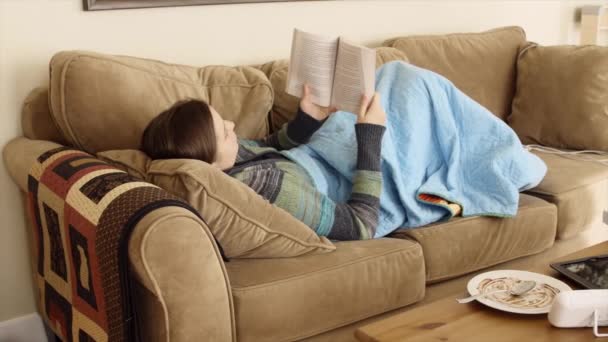 Kvinnan läser bookon en soffa — Stockvideo