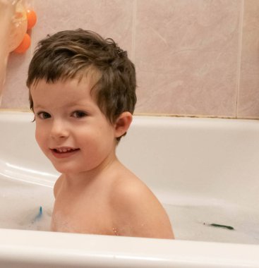 Küçük çocuk tuvalette oyuncaklarla oynuyor.