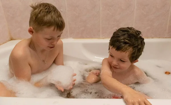 Çocuklar banyoda köpükle oynuyorlar.