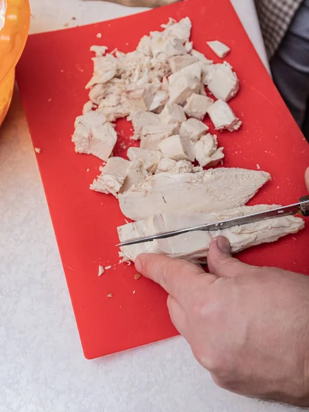 Adam mutfakta tavuk kesiyor.