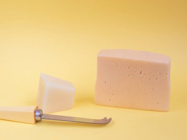 Sarı arka planda taze peynir ve bıçak parçaları.