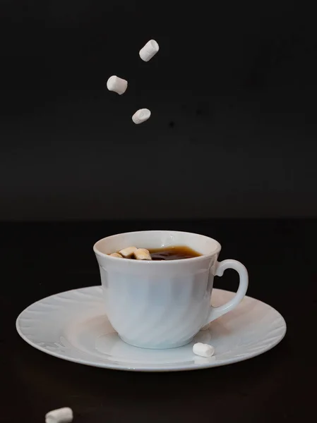 in coffee falls marshmallow on black background