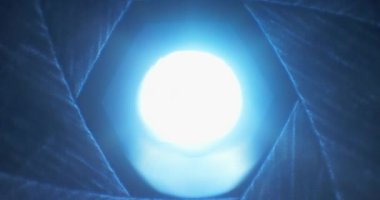 Eski kamera lenslerinden parlayan mavi ışıkla yavaş yavaş açılan Iris bıçakları beyaza dönüşür. Geçiş, soyut kavram.