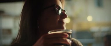 Gün batımında koyu biranın keyfini çıkaran kadın