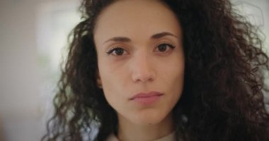 Ciddi görünümlü çok ırklı genç bir kadın.