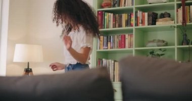Mutlu kadın evde müzik eşliğinde dans ediyor.