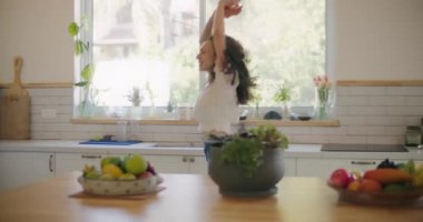 Kıvırcık saçlı kadın dans ediyor, şarkı söylüyor.