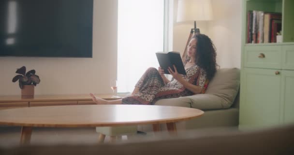 Bir kadın kanepede kitap okumaktan hoşlanır. — Stok video