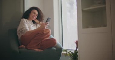 Telefonunu izlerken gülen bir kadın.