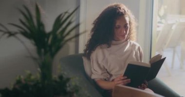 Pencerenin yanında kitap okuyan bir kadın