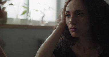 Çok üzgün bir kadın saçına dokunuyor.