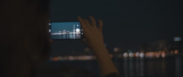 Kvinna tar bilder av en stad på natten — Stockvideo