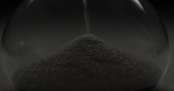 Macro shot of black sand in hourglass — Stock Video