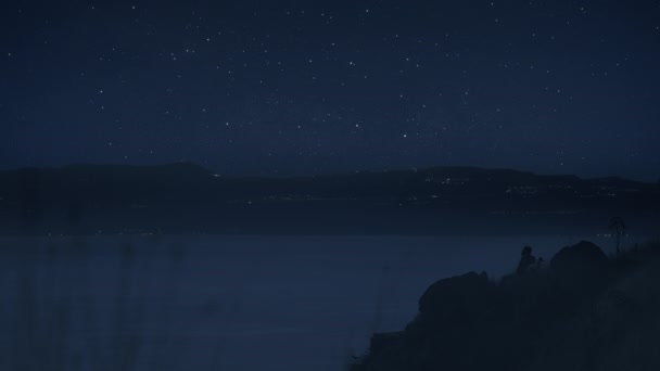 Un nómada digital y su perro disfrutando del cielo nocturno estrellado — Vídeo de stock