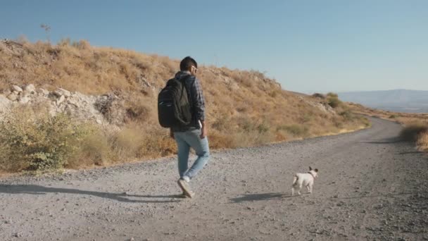 Man walking on the dirt road with a dog — Vídeos de Stock