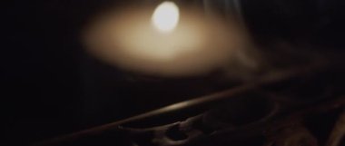 Tütsülerin yanında yanan bir mum.