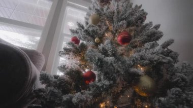 Düşük açılı, süslü ve ışıklandırılmış bir Noel ağacının ev penceresinin yanındaki resmi. Yavaş çekim. 