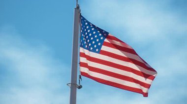 Mavi gökyüzüne karşı rüzgarda dalgalanan Birleşik Devletler bayrağı. Yavaş çekim. 