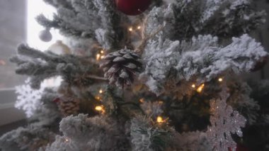 Evde bir Noel ağacının üzerine yapay çam kozalağı süslemesi. Yavaş çekim. 