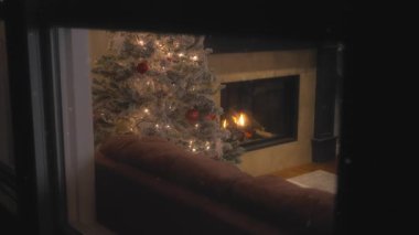 Dışarıda kar yağarken, evde bir Noel ağacının yanında şömine yanıyor. Ağır çekim, ağır çekim.. 