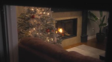 Dışarıda kar yağarken, evde bir Noel ağacının yanında şömine yanıyor. Ağır çekim, ağır çekim.. 