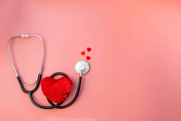 Black stethoscope with red heart of doctor for checkup on pink background. Stethoscope equipment of medical use. Health care and cardiology concept with copy space. Valentines day