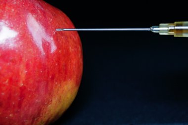 Hypodermic Needle Injecting a Red Apple