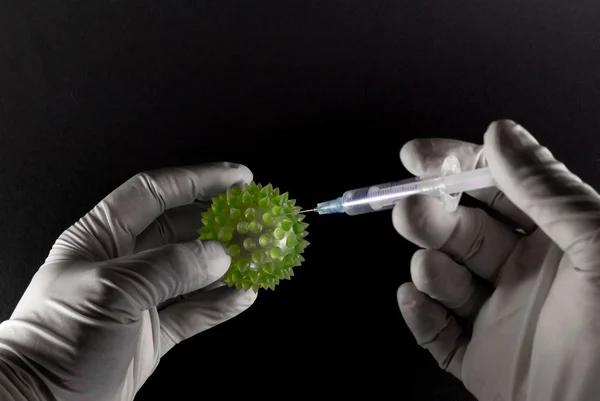 Manos con guantes médicos inyectando un virus verde — Foto de Stock