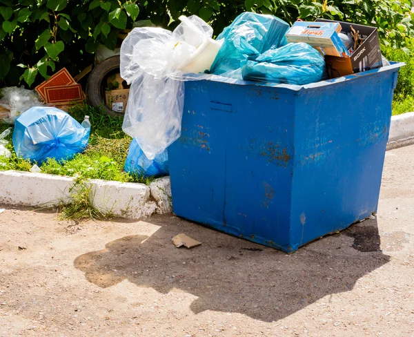 Cubo de basura industrial azul que se desborda con basura — Foto de Stock