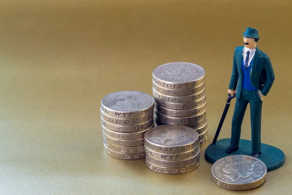 Juguete en miniatura para hombre de negocios e inglés Monedas de una libra — Foto de Stock