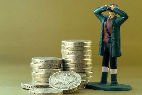 Modelo en miniatura único que mira monedas de libras inglesas — Foto de Stock