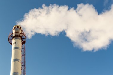 Mavi bir gökyüzüne yükselen baca kirliliği duman