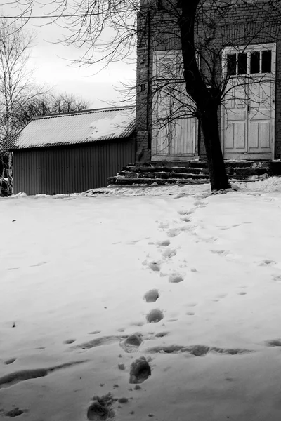 Fotspår på snö och hem — Stockfoto